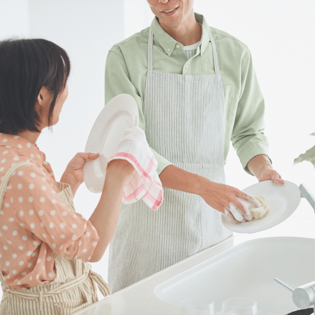 Two people in a brightly lit room working together to clean dishes. This is an example of the additional custom services that Ebb & Spruce offers. 