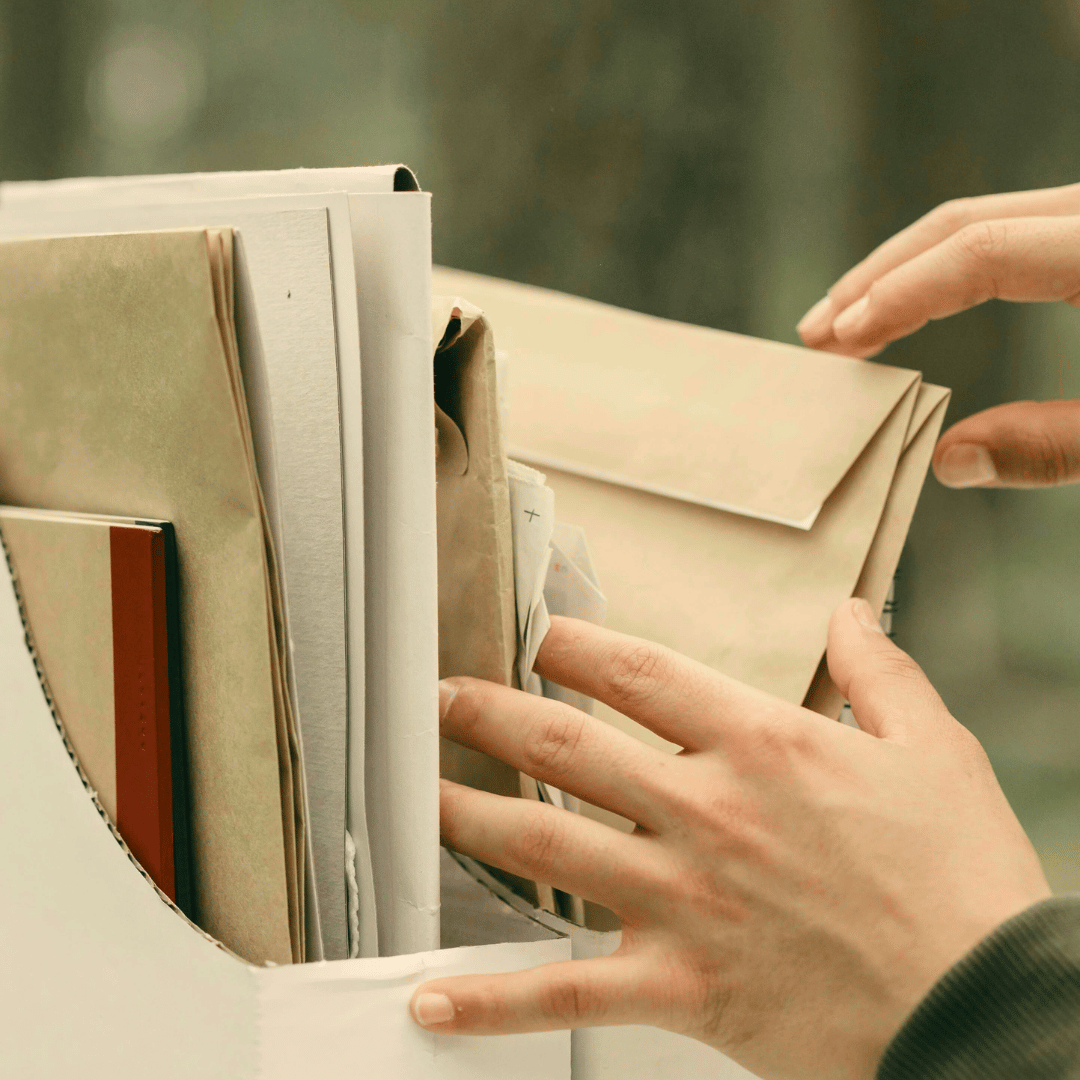 Image of someone outside with greenery in the background. They are going through some papers in a file box. This is an example of the type of service Ebb & Spruce offers. 